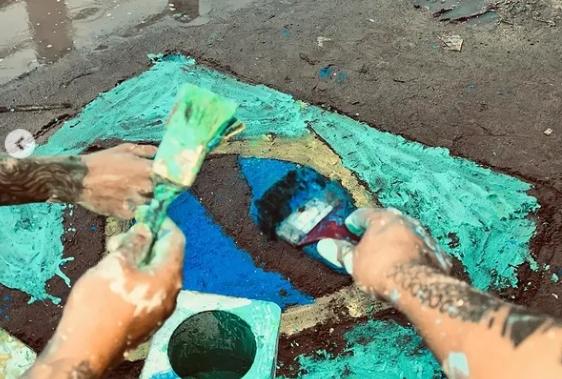 Jovens desenham bandeira do Brasil em rua de lama em Belém